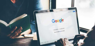 Laptop on Google homepage person reading a book
