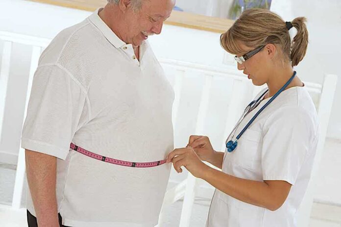 A healthcare professional measuring a patients waist with a tape measure
