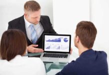 Business professional presenting data on a laptop to two colleagues