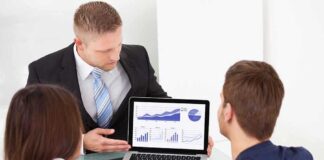 Business professional presenting data on a laptop to two colleagues